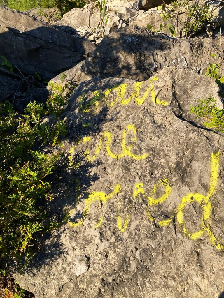 A rock with the words "you are loved" spray painted in yellow